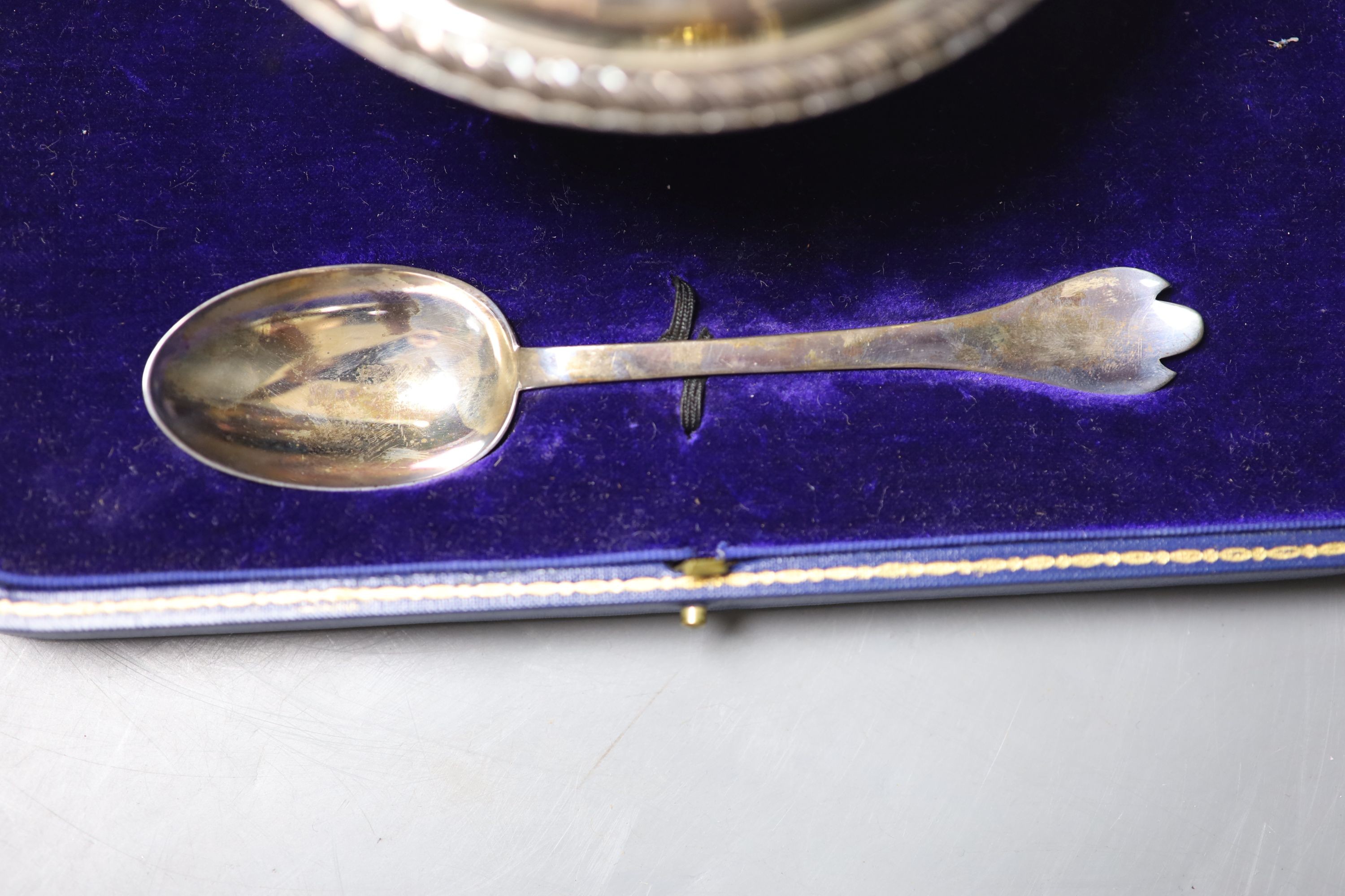 A cased George V silver porringer cup and cover, Carrington & Co, London, 1924, diameter 18.3cm, together with a rat tail trefid spoon, Francis Higgins & Sons Ltd, London, 1924, 170z.